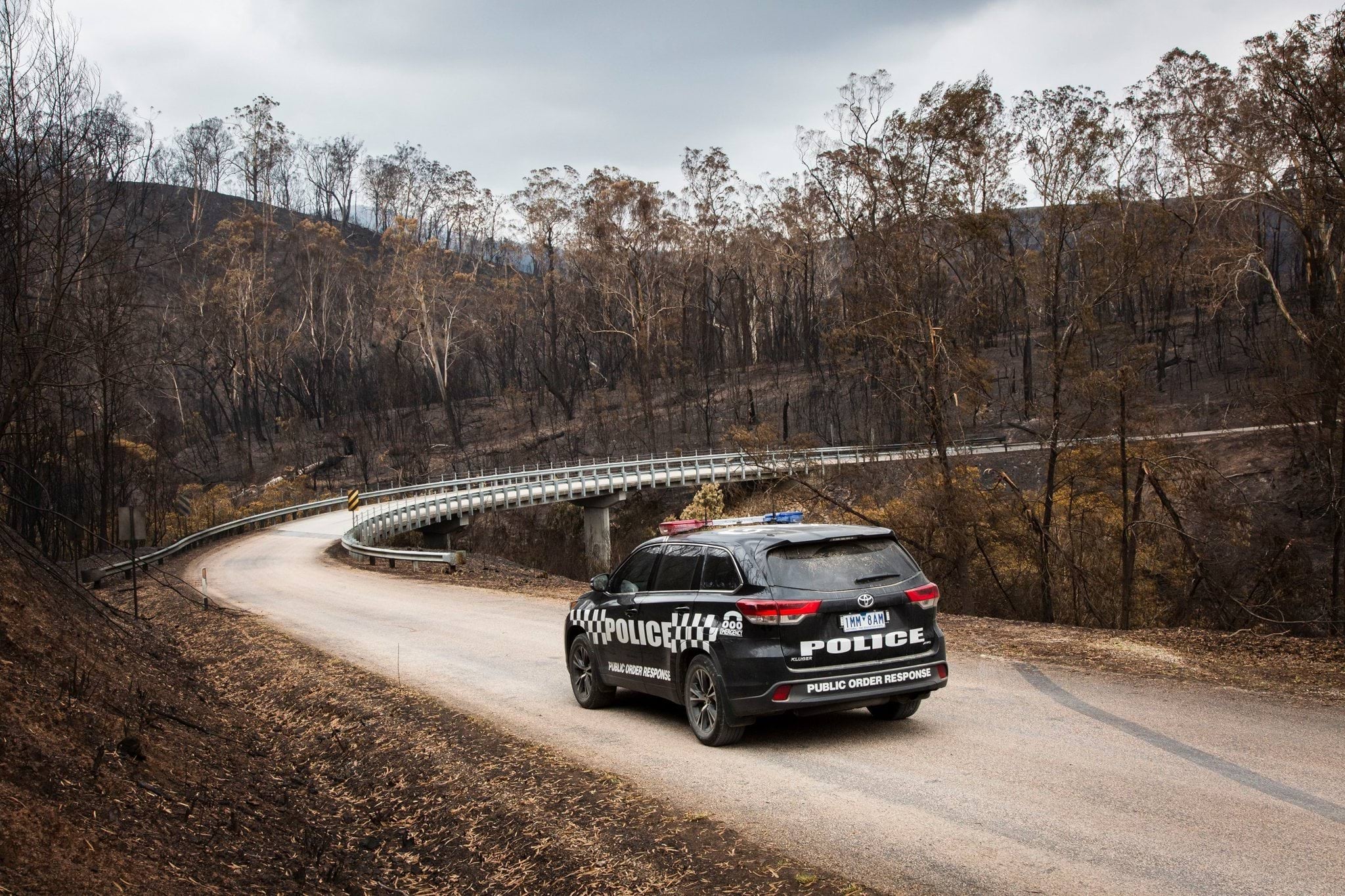 Natural disaster support Lone police car driving through bushfire affected disaster zones.