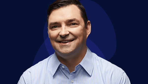 Image of retired police officer smiling to the camera wearing light blue business shirt, no tie. Late forties, Anglo male with dark hair.