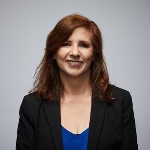 Annette's story Image of police spouse looking at camera wearing a dark blue jacket or blazer. Light skin and auburn hair