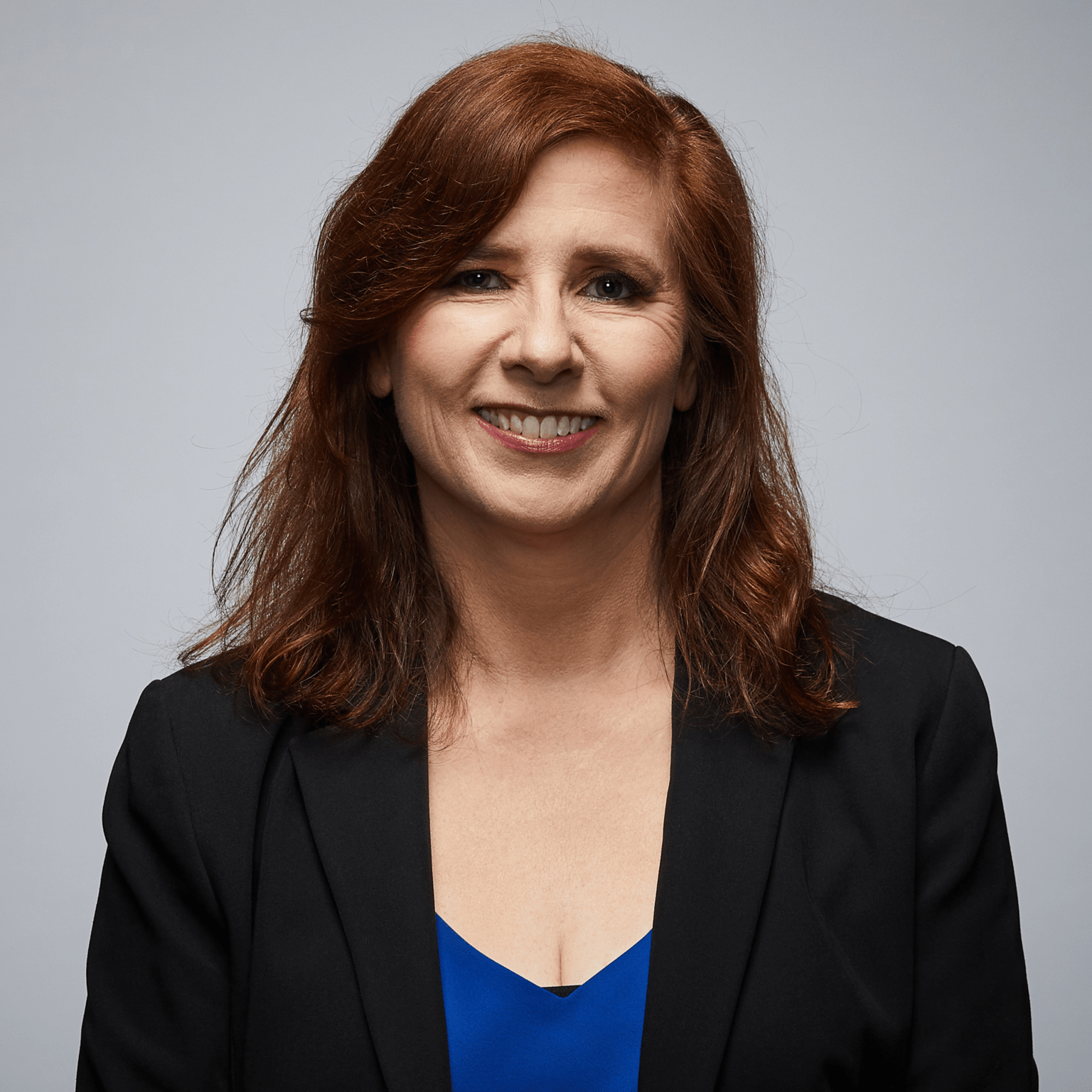 Personal stories - Annette Image of police spouse looking at camera wearing a dark blue jacket or blazer. Light skin and auburn hair