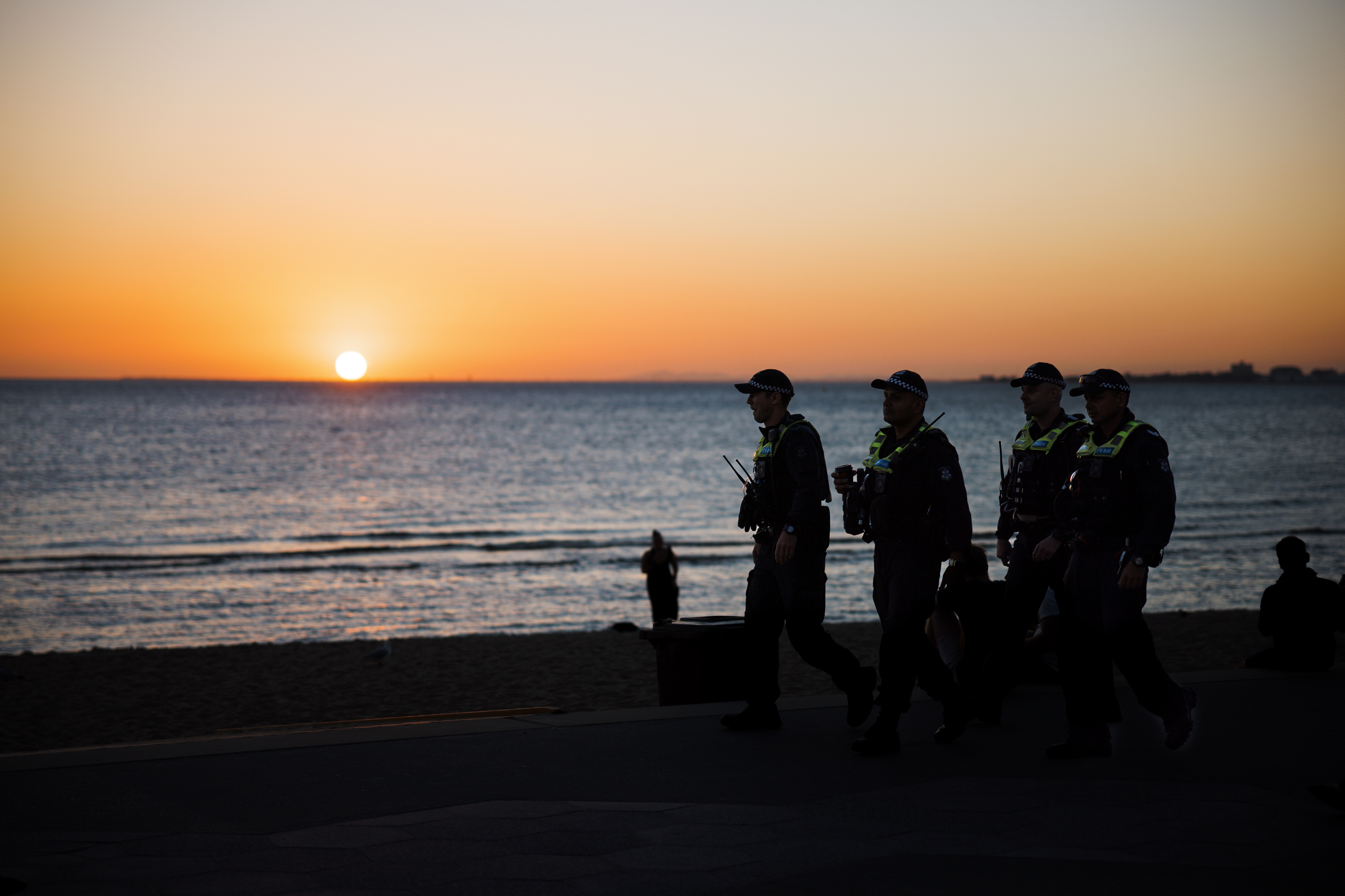 Police and the community Four uniformed police officers patrolling the beach at sunset.